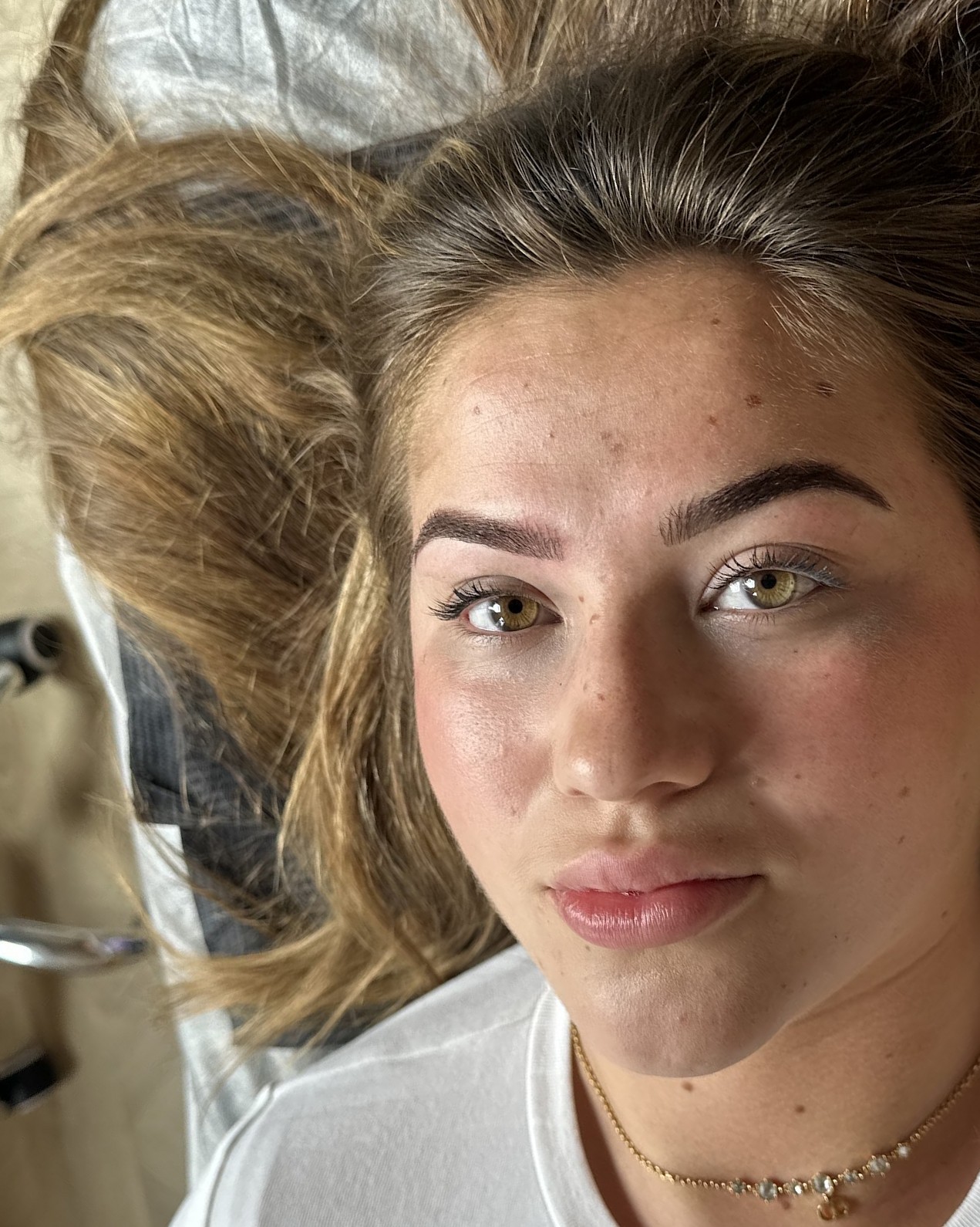 Klant van IC Beauty met haar nieuwe wenkbrauwen, liggend op de behandelstoel